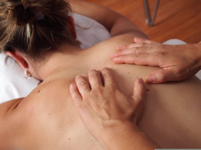 woman getting a back massage while laying face down on a massage table